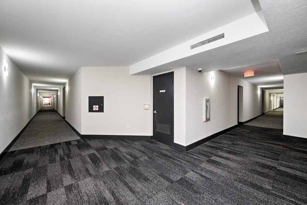 A long hallway with a carpeted floor and white walls.