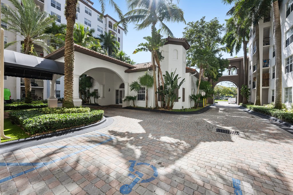 A sunny day at a courtyard with a white arched building and palm trees.