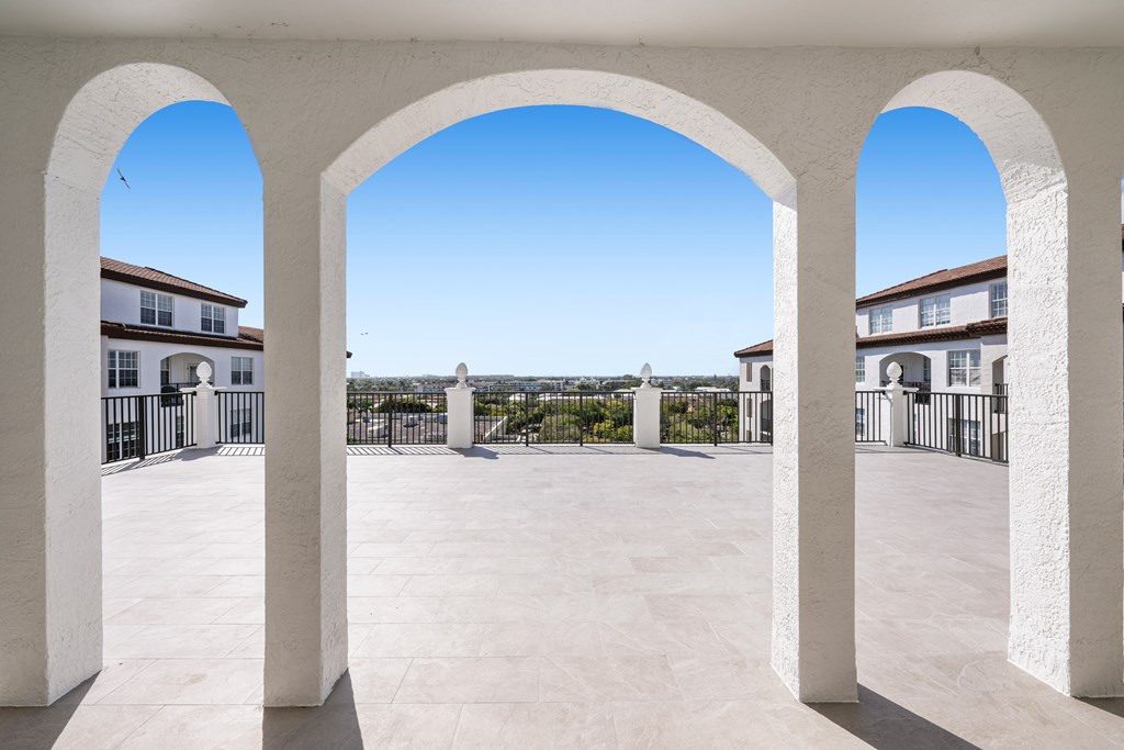 A courtyard with white arches and a clear blue sky.