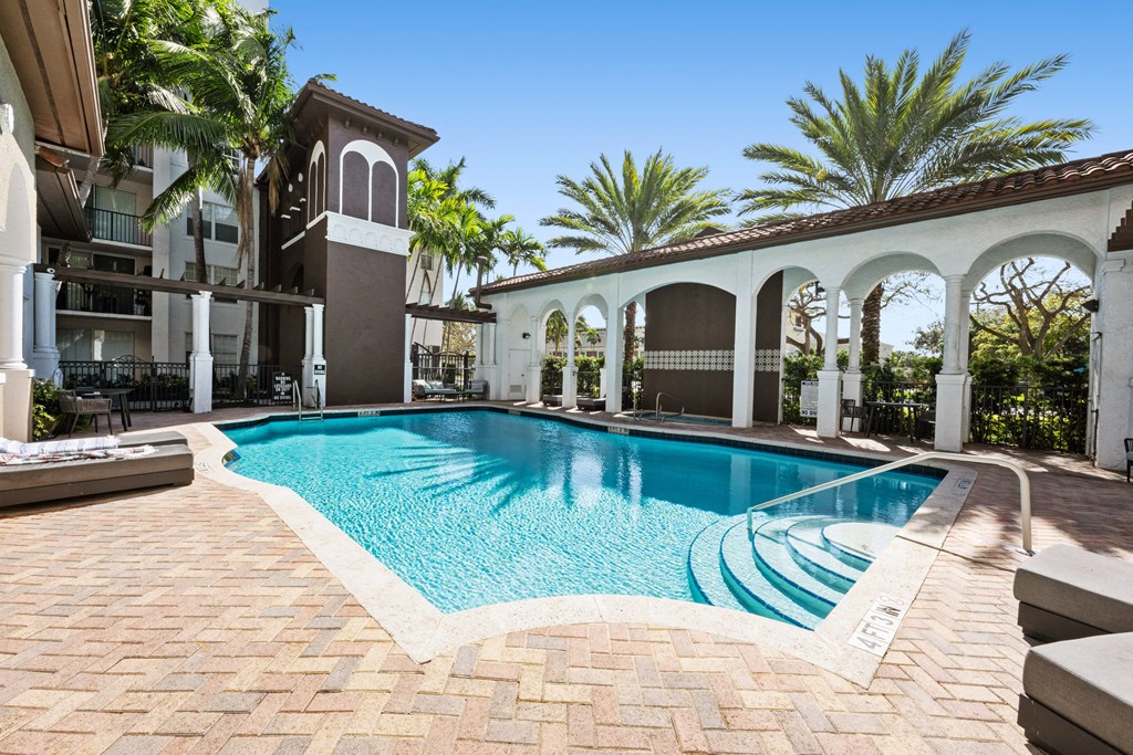 A pool surrounded by a white fence and palm trees.