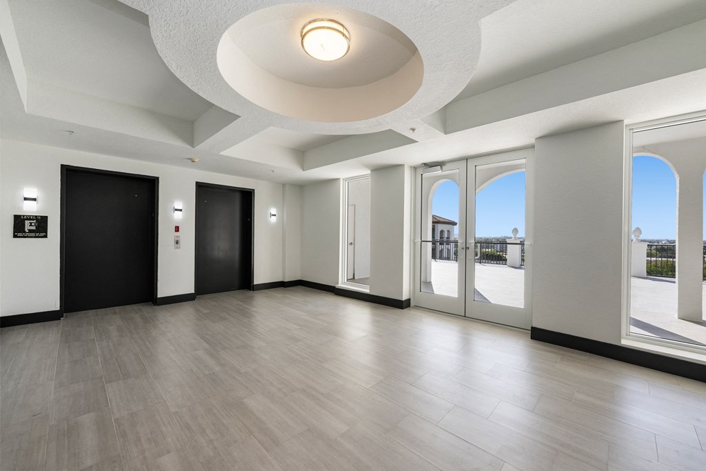 A spacious room with a black door and a white ceiling.