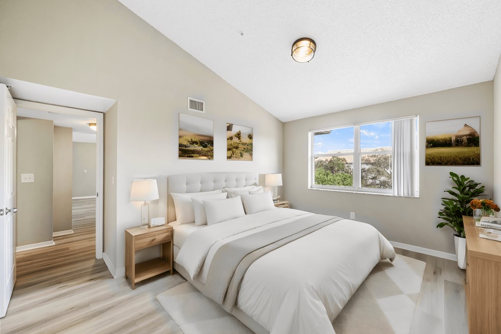 the master bedroom has a large white bed and a window