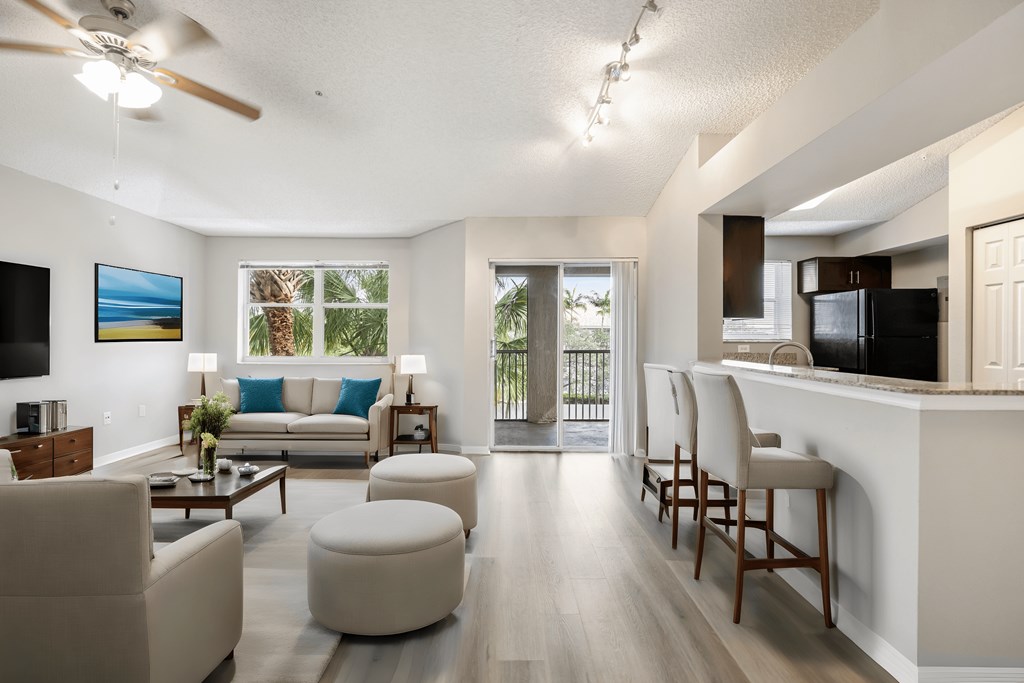 a living room with couches and chairs and a kitchen with a bar and a