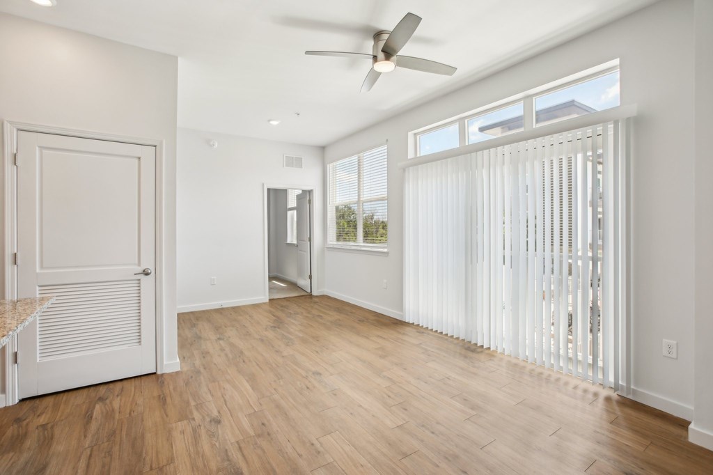 A room with a ceiling fan and a window with blinds.