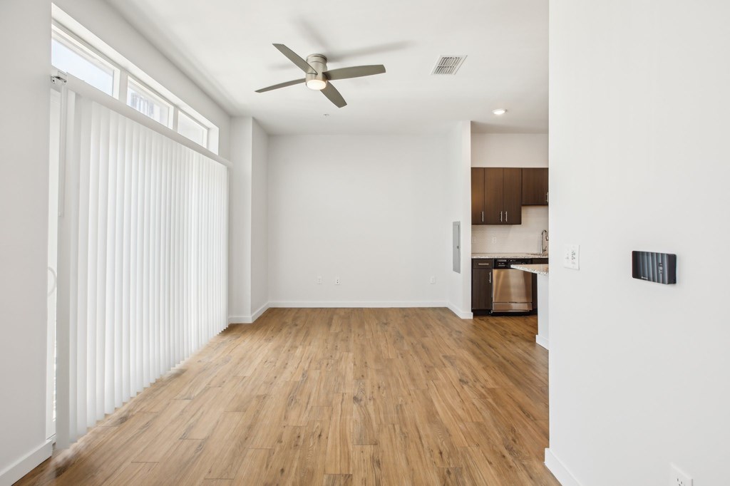 A room with a ceiling fan and wooden flooring.