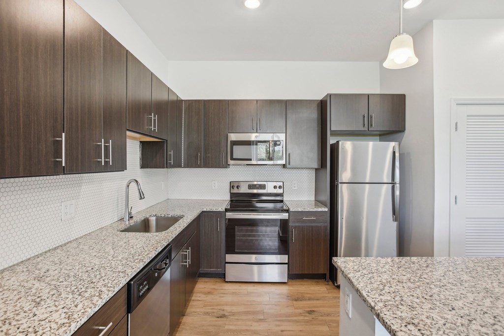 A modern kitchen with dark wood cabinets and stainless steel appliances.