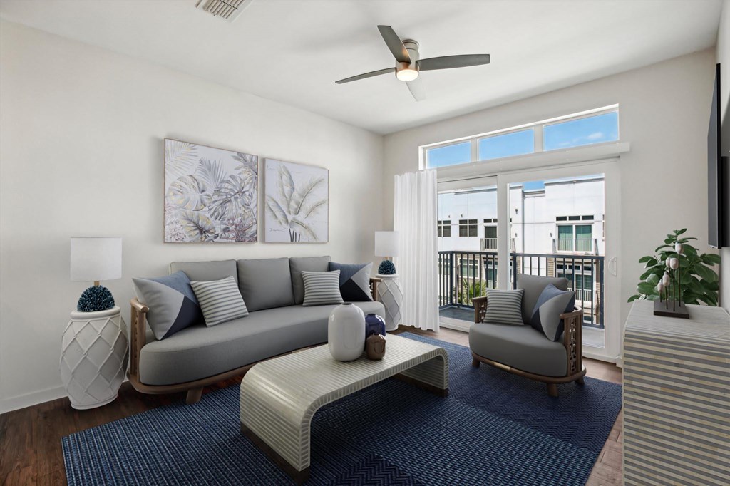 A living room with a grey couch, a white coffee table, and a ceiling fan.