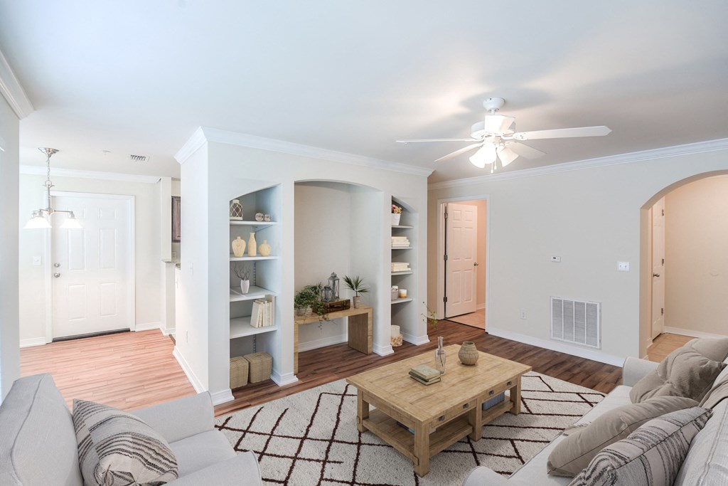 a living room with a ceiling fan and a coffee table in the middle of the room