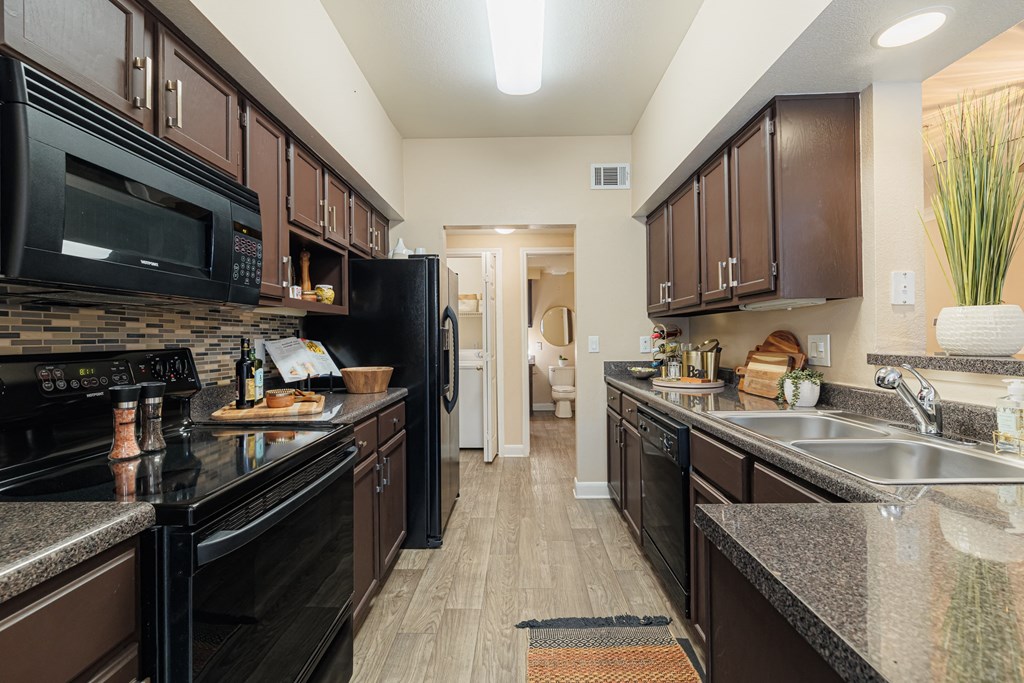 A kitchen with black appliances and brown cabinets.