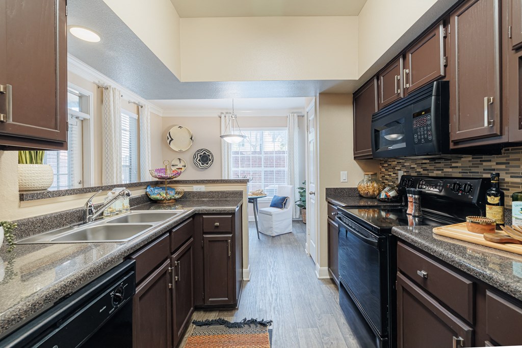 A kitchen with brown cabinets and black appliances.