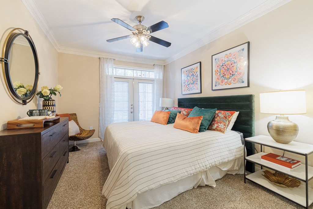 A bedroom with a bed, nightstand, and a ceiling fan.