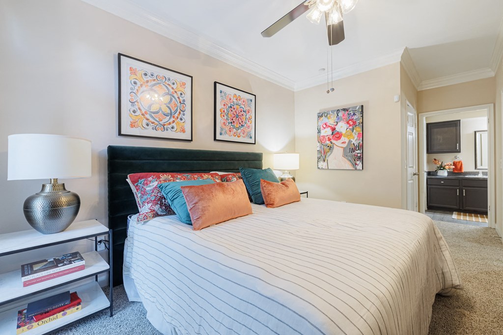 A bedroom with a bed, a nightstand with a lamp, and two framed pictures on the wall.