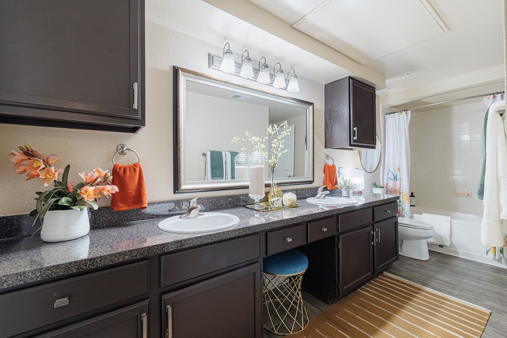 A bathroom with a vanity, sink, mirror, and a chair.