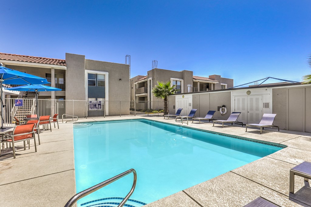 our resort style swimming pool is next to our apartments with chairs and tables