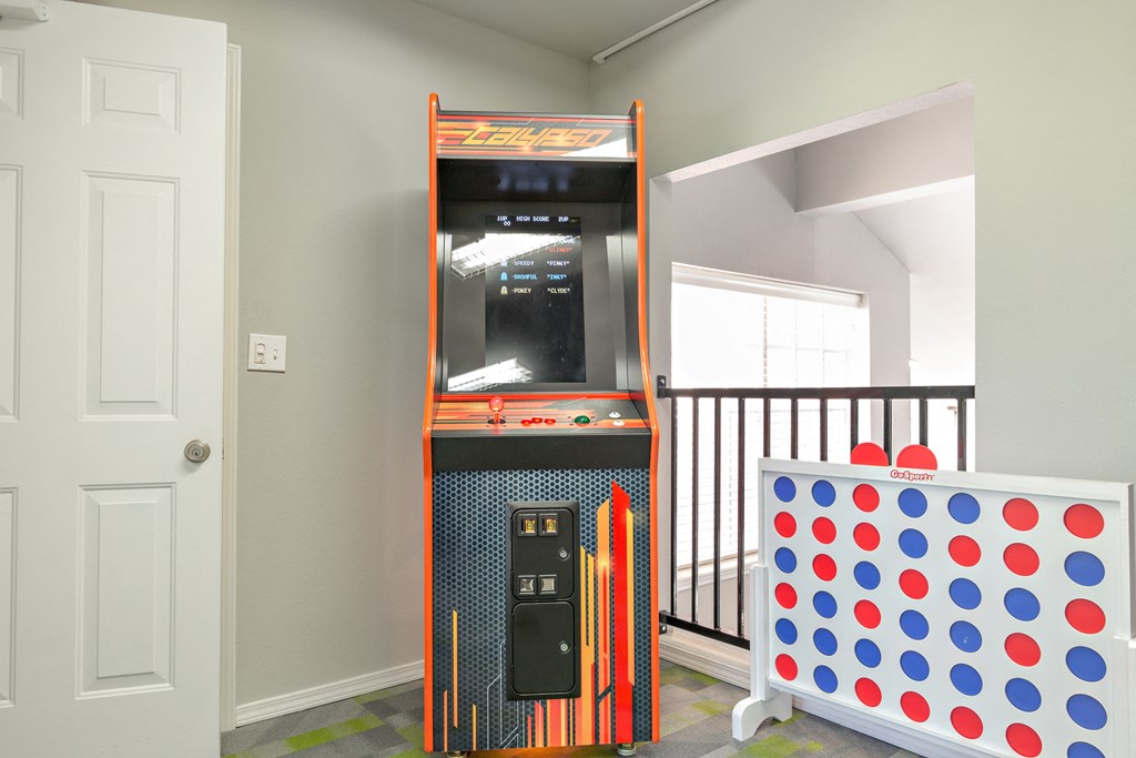 a game room with a video game machine and a table with other equipment