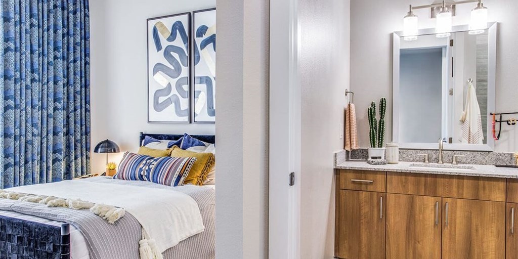 A bedroom with a bed, a mirror, and a painting on the wall.