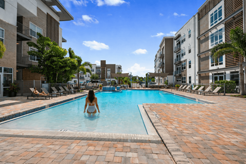 A woman is sitting in a pool surrounded by buildings.