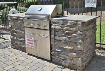 a stone outdoor kitchen with a grill on top of it