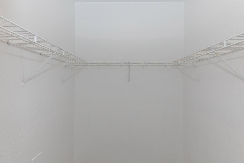 a corner of a room with white walls and a white wire rack hanging from the ceiling