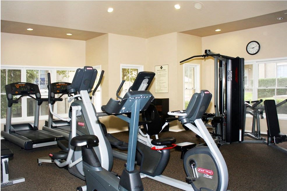 a gym with various exercise machines and a clock on the wall