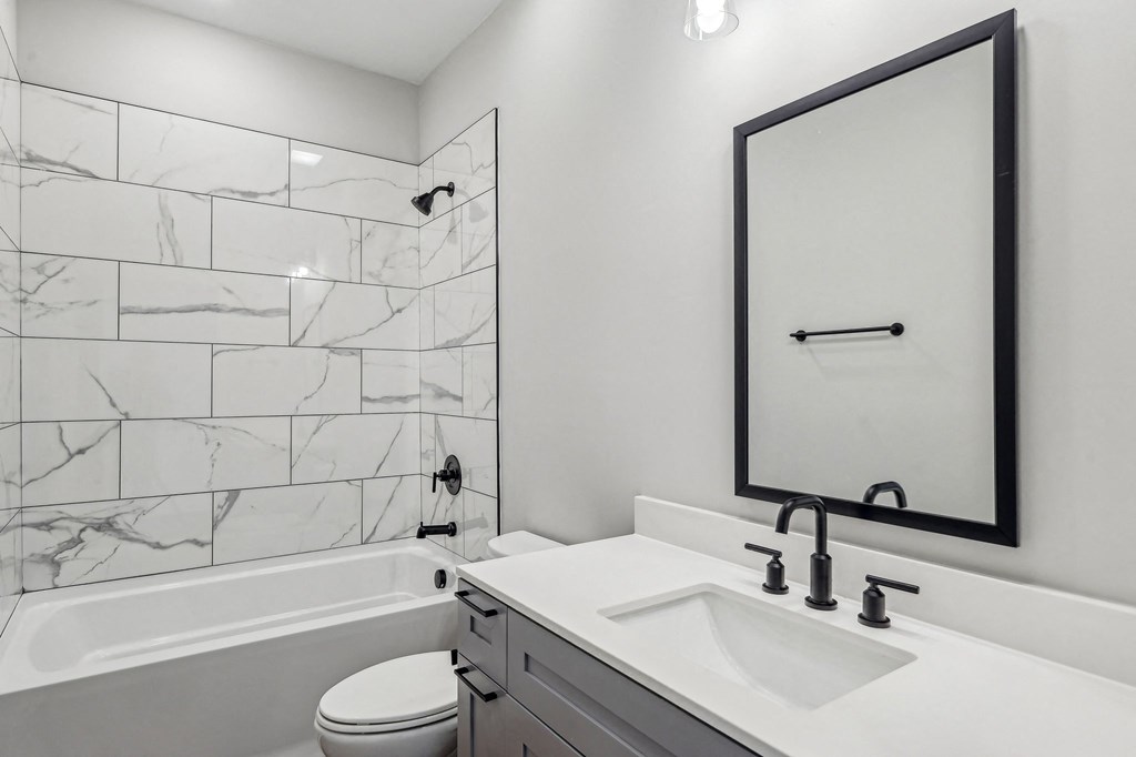 A bathroom with a marble tile wall and a white sink.