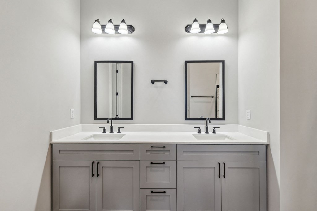 A bathroom with a double sink vanity and two mirrors.