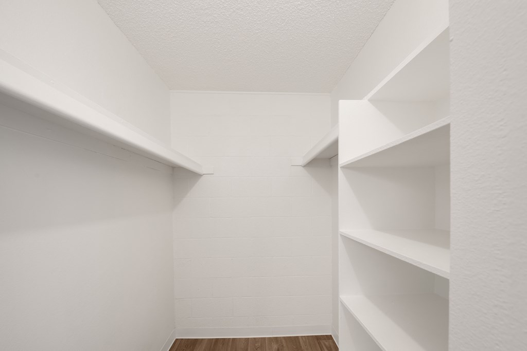 a walk in closet with white walls and shelves