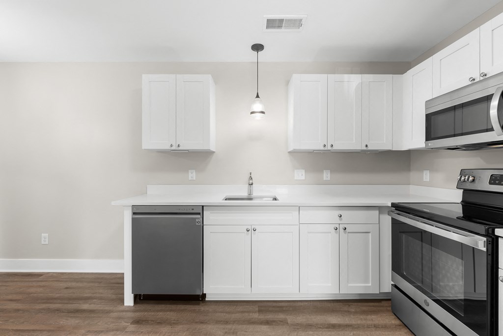 an empty kitchen with white cabinets and stainless steel appliances