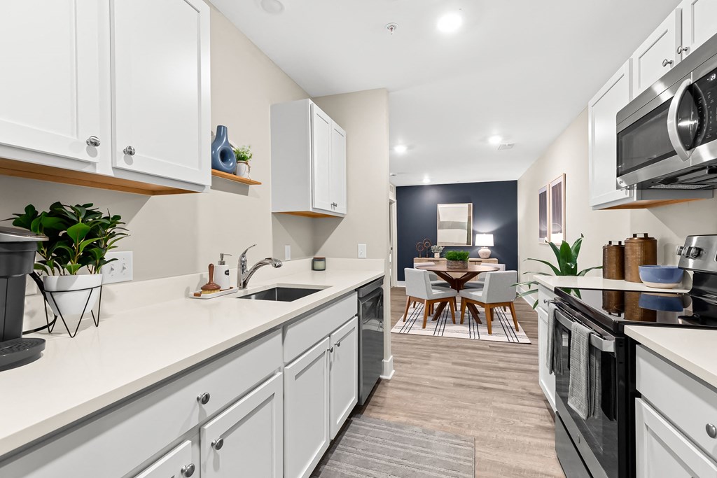 an open kitchen with white cabinets and appliances and a living room with a dining room