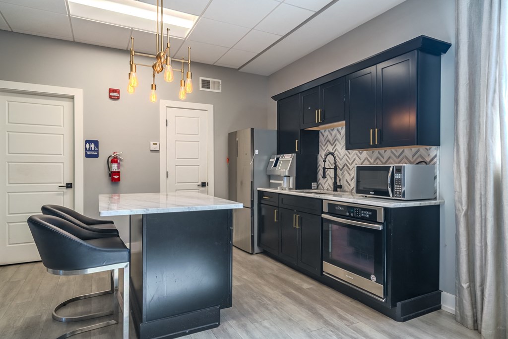 a kitchen with black cabinets and a counter top and a refrigerator