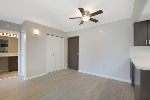 an empty living room with a ceiling fan and a kitchen