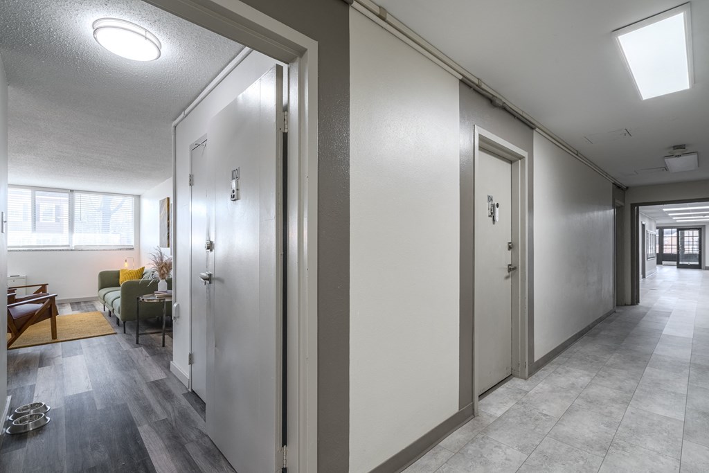 a hallway with white doors and a living room with a couch and a table