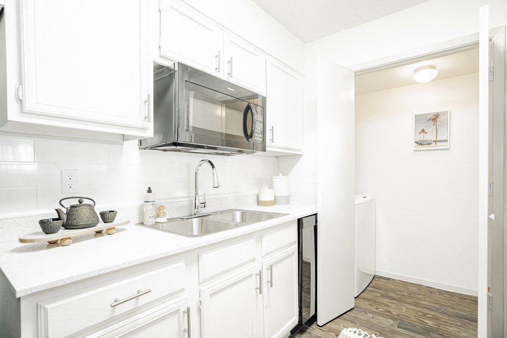 a kitchen with white cabinets and a sink and a microwave