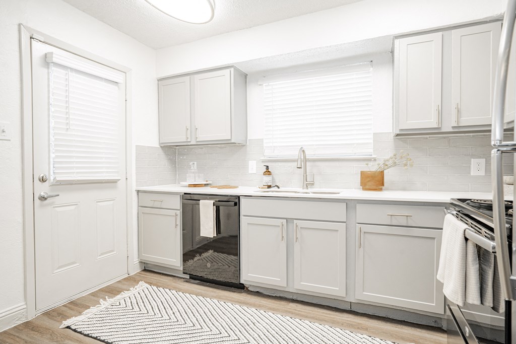 a white kitchen with white cabinets and a stainless steel refrigerator