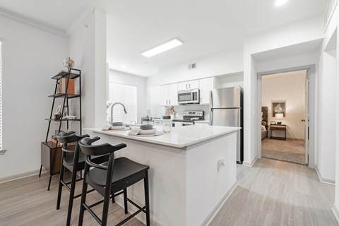 a kitchen with an island and stools in a living room with a refrigerator