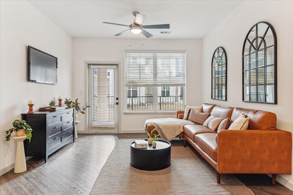 a living room with a leather couch and a ceiling fan