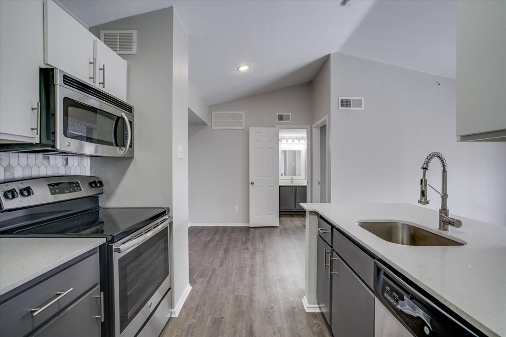 an empty kitchen with stainless steel appliances and a sink