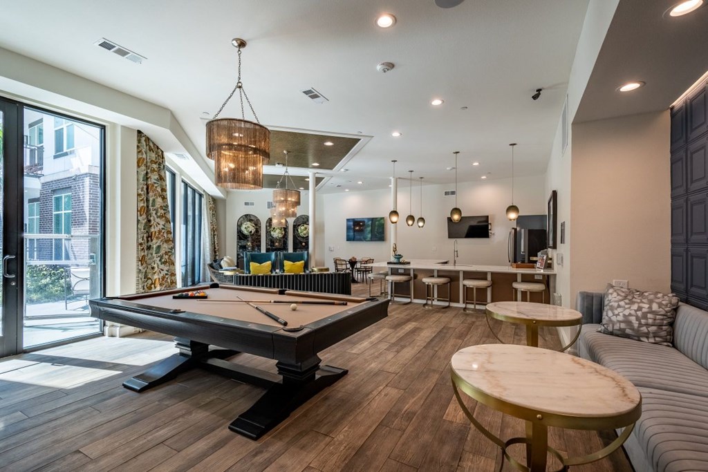 A billiard table is in the middle of a room with a couch and a table.