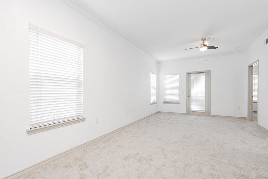 an empty living room with white walls and a ceiling fan