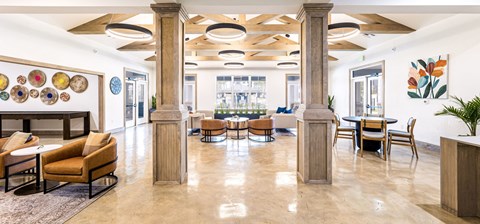 A spacious lobby with a fireplace, chairs, and tables.
