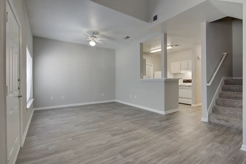 A spacious room with wooden flooring and a staircase leading to another room.