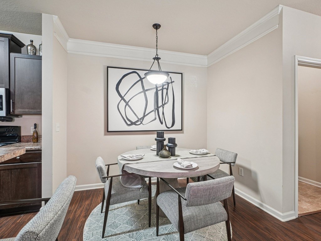 A dining room with a table set for two and a modern art piece on the wall.