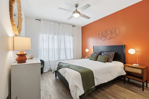 A bedroom with a bed, nightstand, and a ceiling fan.