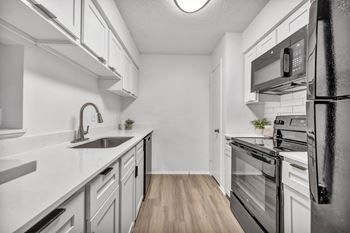 A modern kitchen with a sink, stove, and refrigerator.