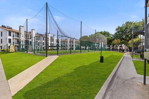 a grassy area with a playground and buildings in the background