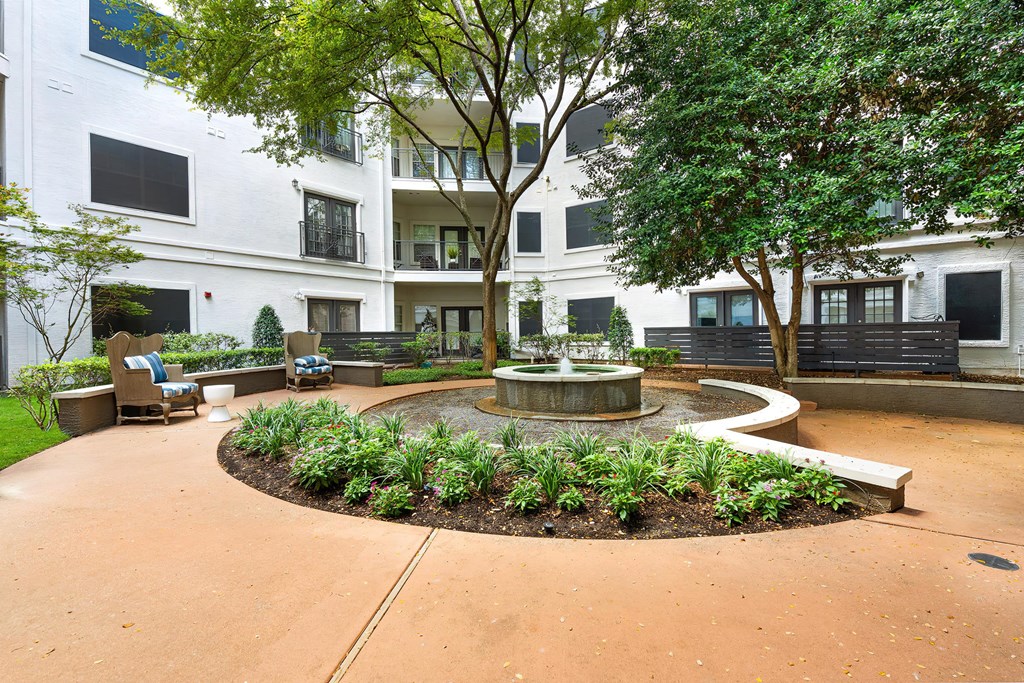 a courtyard with a fountain and trees in front of an apartment building