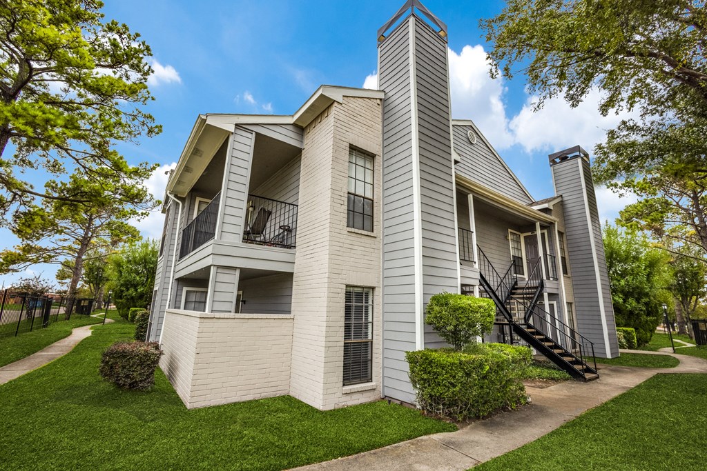 the view of a white and gray house with trees and grass