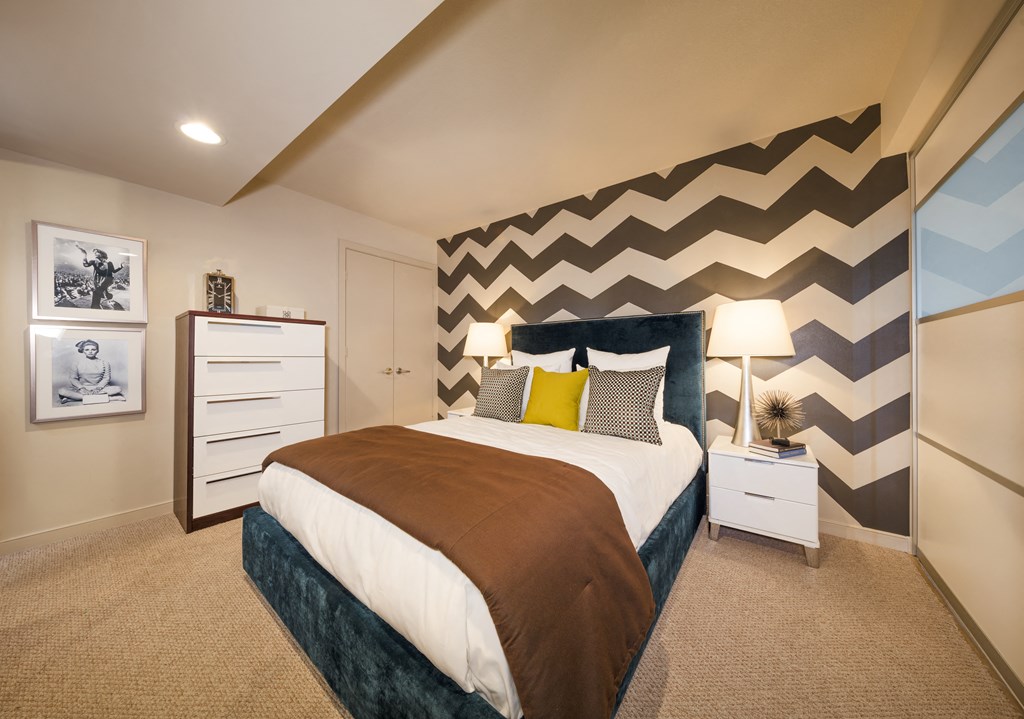 A bedroom with a large bed and a chevron patterned wallpaper.