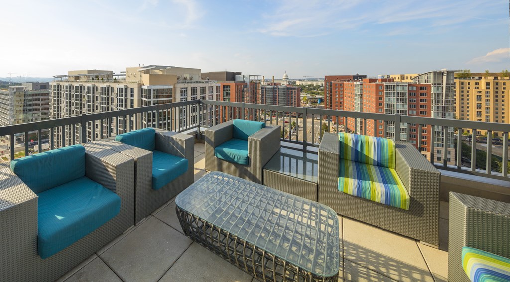 A patio with blue cushions and a woven table.