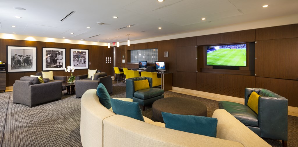 A room with a large screen TV and comfortable seating.